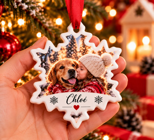 Flocon de Noël en céramique tenu en main, avec la photo d'une petite fille embrassant un chien et le prénom Chloé